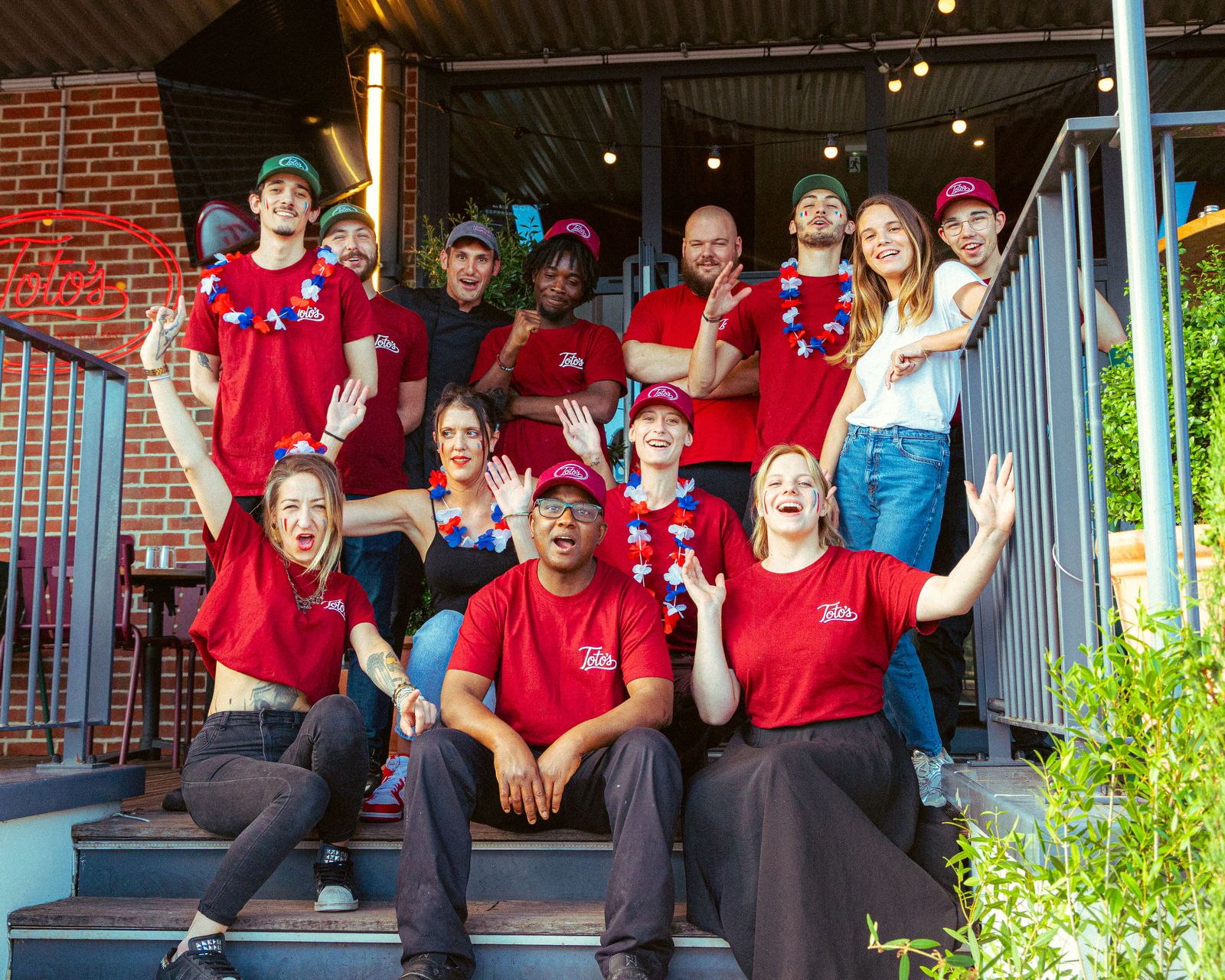 Toute l'équipe de Toto's en t-shirt rouge devant le restaurant